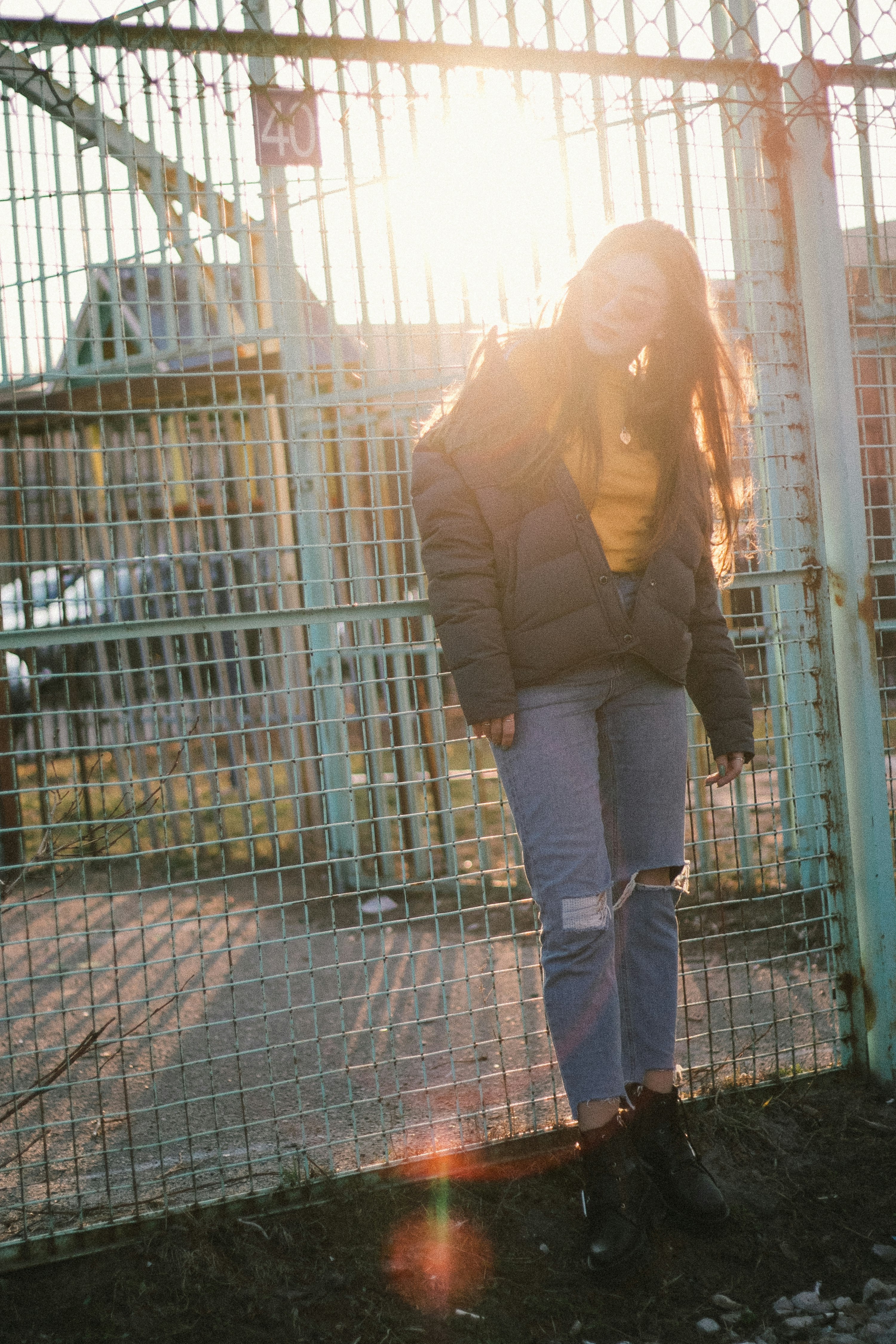 woman in brown jacket standing beside white metal fence